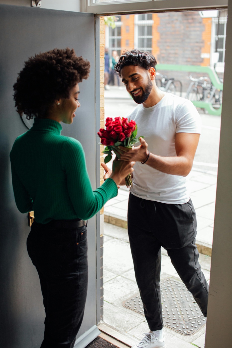 A man giving roses to his partner at the door